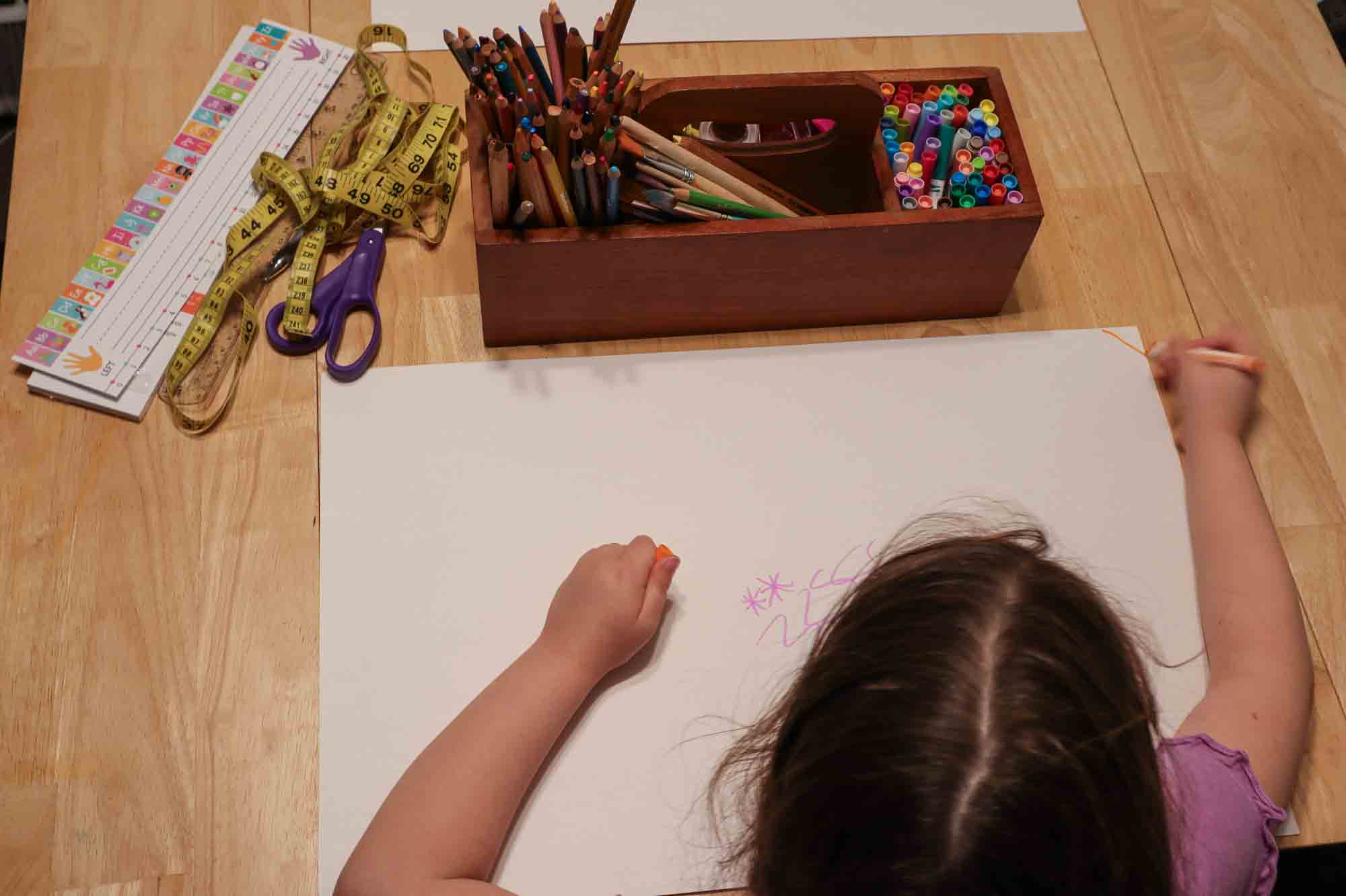 Process shot of decorating homemade placemat with markers.