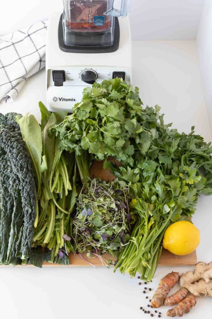 Tray full of leafy greens with high powered blender in the background.