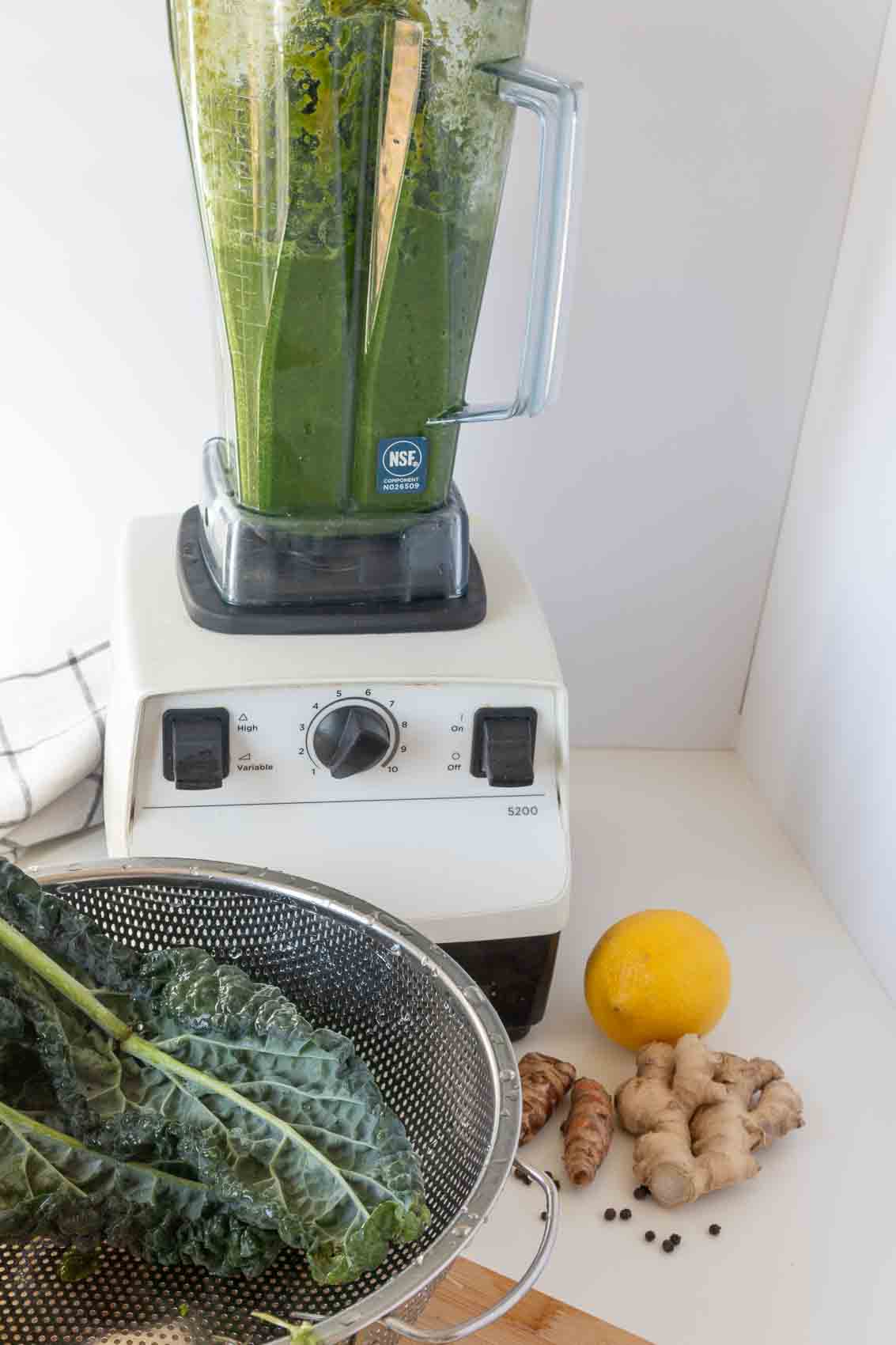 Process shot of adding greens to running blender.
