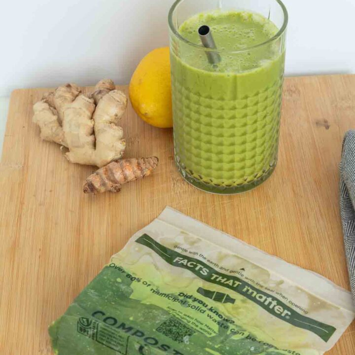 Green smoothie in a glass with a bag of frozen green juice.